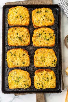 several square pieces of bread with cheese and herbs on them sitting on a cooling rack