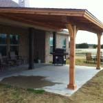 an outdoor covered patio area with chairs and grill in the backgroung,