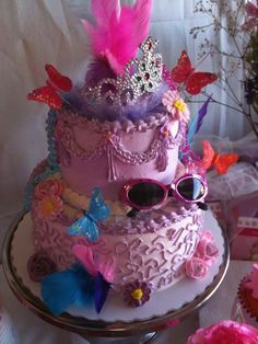 a three tiered cake decorated with pink and purple decorations