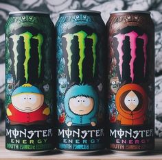 three cans of monster energy drink sitting on a table next to each other with the same character