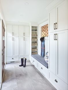 a walk in closet filled with lots of white cupboards and boots on top of it