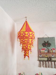 there is a yellow and red umbrella hanging from the ceiling in this room with two pictures on the wall