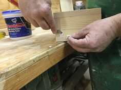 a man is working on some wood with a pair of scissors in his left hand