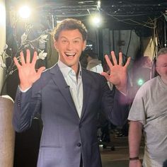 a man standing in front of a camera holding his hands up