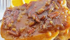 two pieces of pecan bread covered in gravy on a plate with orange wedges