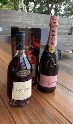 two bottles of wine sitting on top of a wooden table next to an empty box