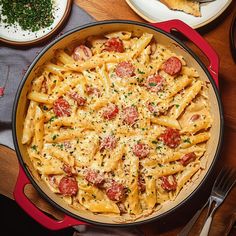 a pan filled with pasta covered in cheese and tomatoes on top of a wooden table