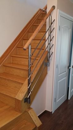 a wooden stair case with metal handrails in a home entryway, next to a white door