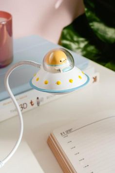 a desk with a book and a lamp on top of it next to a cup