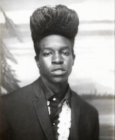 a black and white photo of a young man in a suit with a tie on