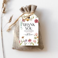 a thank you tag on top of a burlock bag with flowers around it