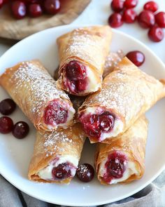 cranberry turnovers on a plate with powdered sugar and fresh cherries