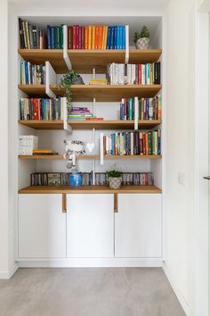 a bookshelf filled with lots of books next to a white wall and door