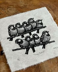 a drawing of five birds sitting on top of a piece of white paper with black ink