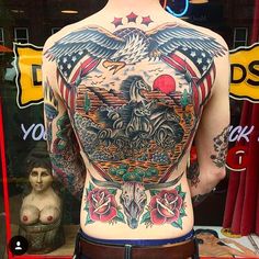 the back of a man's body with an eagle and flowers tattoo on it