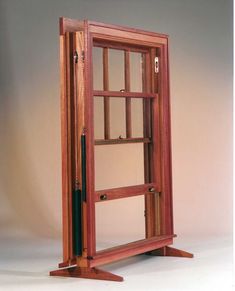 an open wooden book case sitting on top of a white floor next to a wall