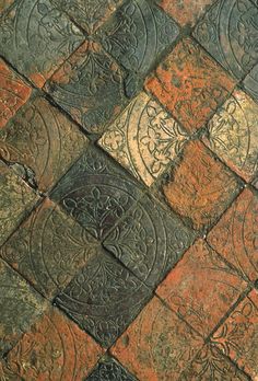 a close up view of an old tile floor with different colors and designs on it