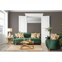 a living room filled with green couches and pillows on top of a wooden floor