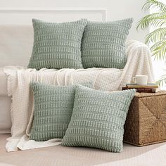 two green pillows sitting on top of a bed next to a wicker basket and blanket