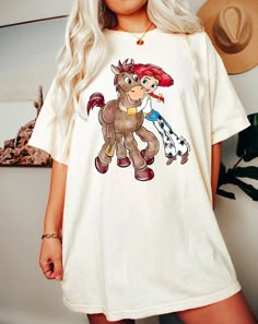 a woman wearing a white t - shirt with an image of a pony on it