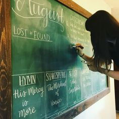 a woman writing on a blackboard with chalk