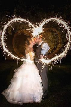 a bride and groom kissing with sparklers in the shape of a heart