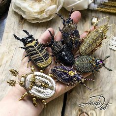 a person's hand holding several beaded bracelets on top of a wooden table