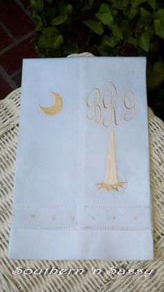 a white paper bag with gold monogrammed letters and a sailboat on it