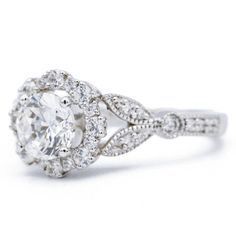 a white gold ring with an oval cut diamond surrounded by round brilliant pave diamonds