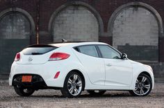 a white car parked in front of a brick building