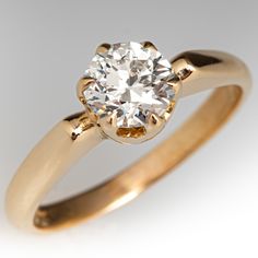 a yellow gold engagement ring with an old - cut diamond in the center, on a white background