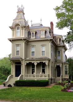 an old victorian style house in the middle of a grassy area with stairs leading up to it