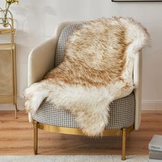 a chair with a furry blanket on top of it in front of a wall and floor