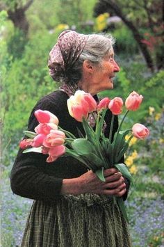 an old woman holding flowers in her hands