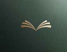 an open book with gold foiling on the front and back cover, sitting on top of a green surface