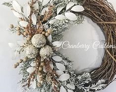 a wreath with white flowers and snow on it is hanging from the side of a wall