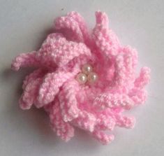 a crocheted pink flower with a pearl in the center