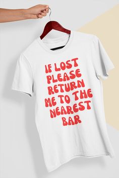 Get ready to make a statement with this hilarious "If Lost, Return Me to the Nearest Bar" t-shirt. Perfect for any party animal, this shirt is the perfect accessory for a night out with friends or a casual day out. Made from soft, comfortable cotton, this shirt will keep you looking and feeling great all day long. Whether you're a beer lover, wine enthusiast, or just love a good cocktail, this shirt is the perfect way to show off your love for a good time. With its unique design and clever messa Drinking Tshirt Ideas, Funny Red Screen Printed Top, Funny Red Top With Screen Print, Funny Red Tops With Screen Print, Funny Red Screen Print Tops, Bar Tshirt Ideas, Fun Crew Neck Shirt With Funny Text, Fun Slogan Crew Neck Top, White Band Merch Top With Funny Text