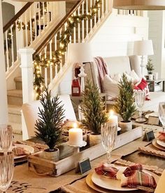 a table set for christmas with candles, plates and napkins on top of it