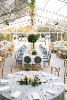 the tables are set up for an elegant wedding reception with blue chairs and white linens