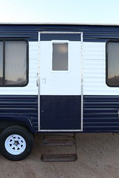 a blue and white trailer is parked in the dirt