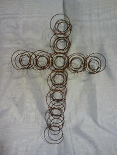 a cross made out of wire with circles around it on a white sheeted surface