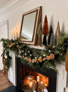 a fireplace decorated for christmas with candles and garland