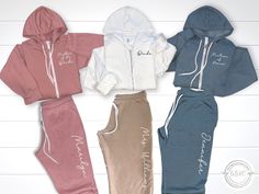 four different colored tracksuits with hoodies and pants on top of each other