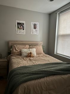 a bedroom with a bed and two pictures on the wall above it, along with a stuffed dog