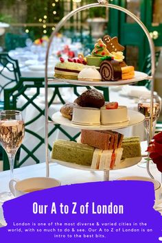 a three tiered tray with cakes and desserts on it next to a glass of wine