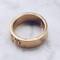 Indonesia Balinese script writing on a rugged band in a gold toned glossy brass. Bali was first inhabited around 2000 BC and has a rich culture rooted in spiritual beliefs. Available in 925 Sterling Silver https://etsy.me/2HlwWyy Ring Size Available in all sizes. Please be sure to find your exact ring size for the finger you want before ordering. See image chart above or you can use the chart on my website as a guide - https://jewelrylab.co/pages/ring-sizing-tips A note about brass jewelry and o Gold Engraved Ring With Wide Band Stamped 14k, Gold Etched Brass Rings, Classic Brass Engraved Ring For Promise, Brass Engraved Ring For Promise, Spiritual Yellow Gold Engraved Ring In Brass, Spiritual Engraved Yellow Gold Ring In Brass, Gold Spiritual Signet Ring For Promise, Symbolic Brass Engraved Ring For Anniversary, Spiritual Gold Signet Ring For Promise