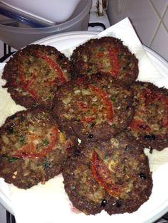 a white plate topped with meat patties covered in toppings