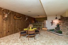 a dining room table and chairs with deer heads on the wall