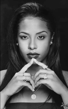 a black and white photo of a woman making the shape of a heart with her hands